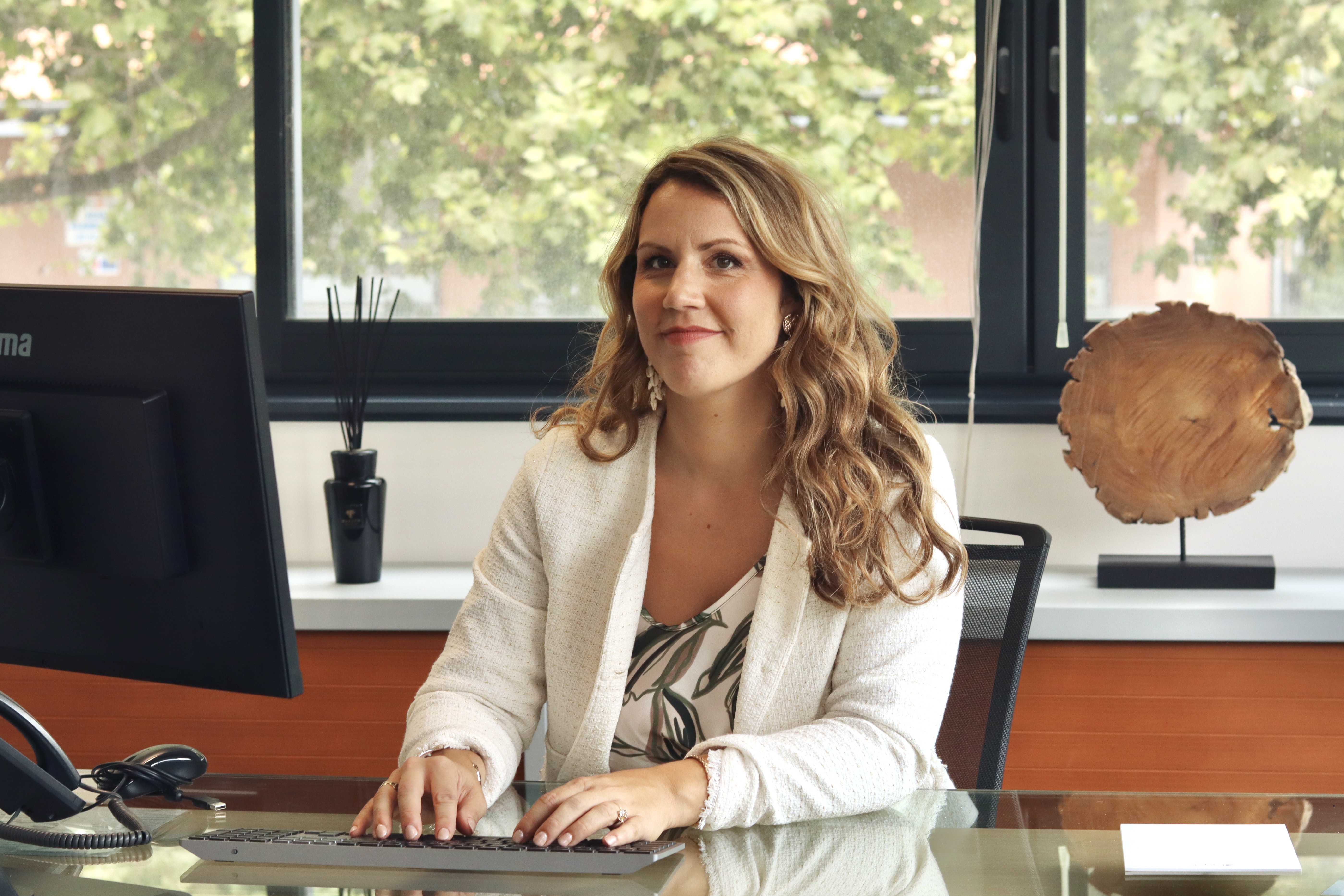 Femme travaillant à un bureau avec ordinateur et téléphone.